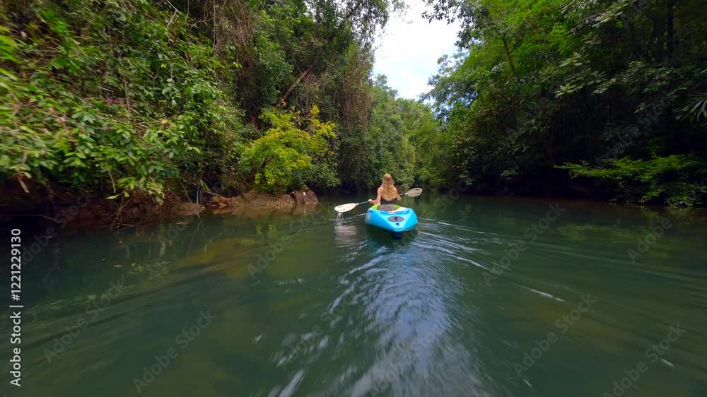 Woman kayaking on a river in a tropical rainforest in Thailand Woman kayaking on a river in a tropical rainforest in Thailand