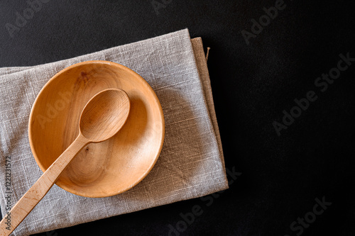 Wooden spoon and plate on a napkin stand on a black table