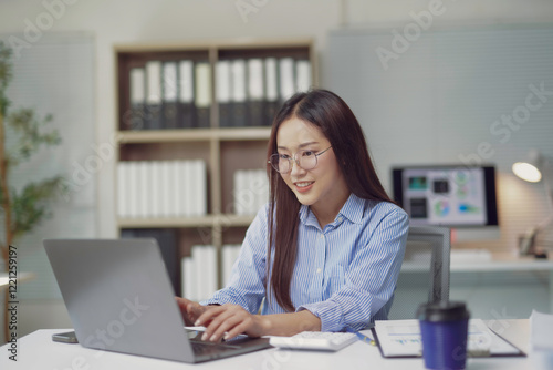Free Download Young Asian businesswoman working on laptop in modern office - GFXLoad
