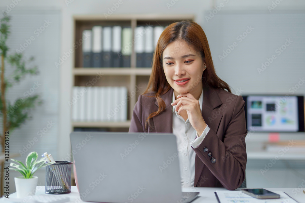 Young Asian businesswoman smiling and working using laptop computer in modern office Young Asian businesswoman smiling and working using laptop computer in modern office