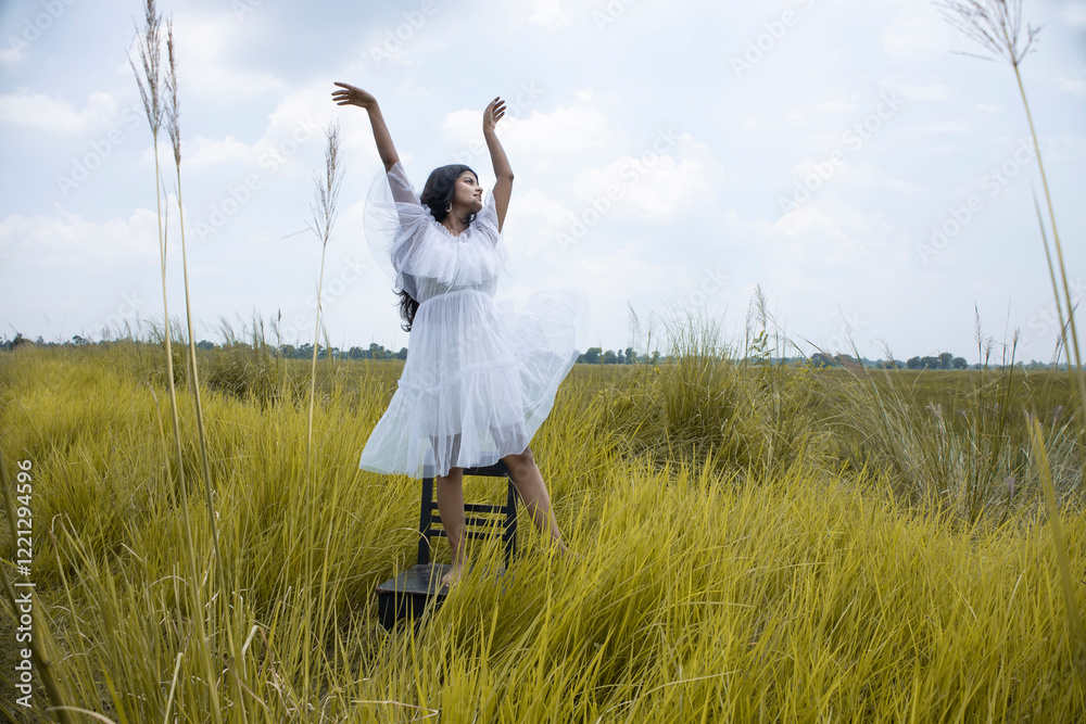 a young Indian female model with black hair, wheatish skin, Indian features wearing a white skirt and posing int he middle of an open grass field a young Indian female model with black hair, wheatish skin, Indian features wearing a white skirt and posing int he middle of an open grass field