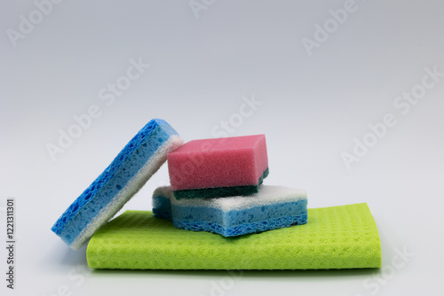View of three colorful kitchen sponges stacked on a light green towel on a light background