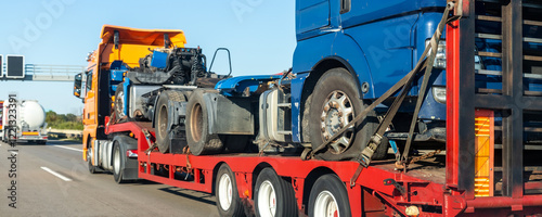 POV heavy industrial truck semi trailer flatbed platform transport wrecked salvage lorry chassis and cabin machine on common highway road at bright day sky. Scrap collision vehicles disposal service photo