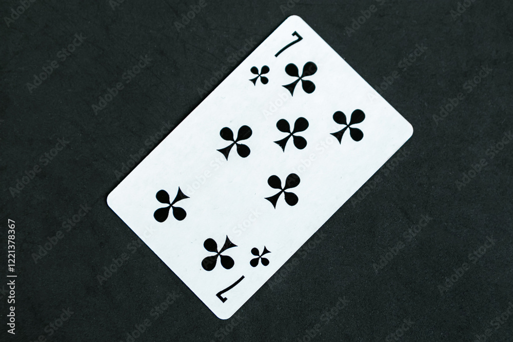 Seven of Clubs playing card, black background, top view Seven of Clubs playing card, black background, top view