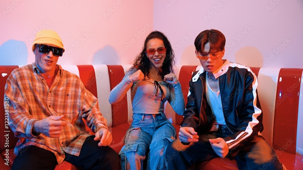 Happy girl looking at camera and moving to pop music while sitting at sofa restaurant. Hispanic woman staring at camera while dancing to freestyle beat with diverse friend in neon light. Regalement. Happy girl looking at camera and moving to pop music while sitting at sofa restaurant. Hispanic woman staring at camera while dancing to freestyle beat with diverse friend in neon light. Regalement.