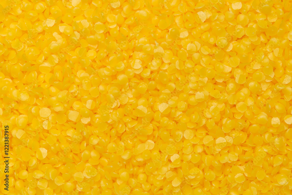 Top view of yellow beeswax pellets, ideal for candle making or crafting. Smooth texture, wax background.