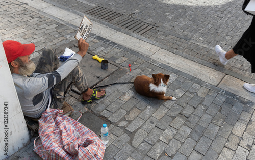 Fototapeta Naklejka Na Ścianę i Meble -  Homeless man with dog begging in the street holding cardboard sign asking for food.