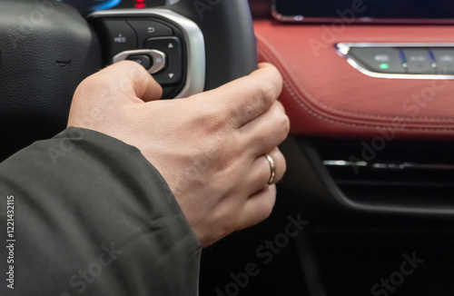 Driver pressing volume button of car radio on steering wheel of a car. Close-up of a man pressing a button on the steering wheel in a car. Man is adjusting radio by buttons on steering wheel.  photo