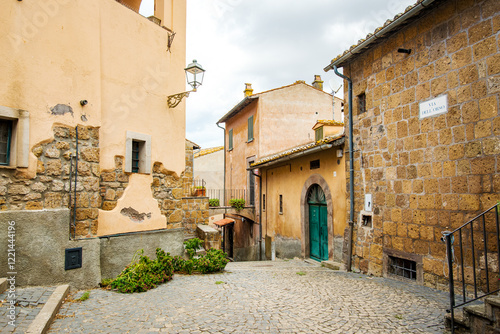 The charming Via del Corso in Tuscania, Italy, showcases a picturesque scene of old buildings with weathered facades and cobblestone paving, creating a timeless atmosphere in this historic town photo