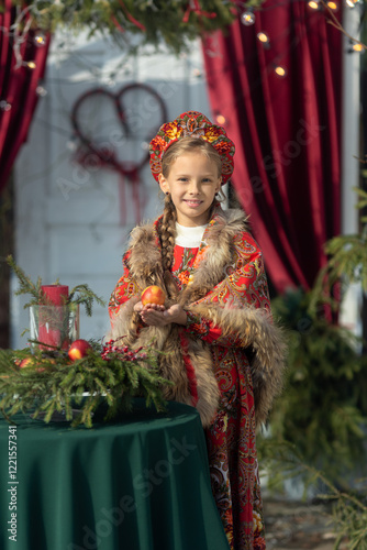 A blonde girl in a national Russian costume on the Maslenitsa holiday. A child in a traditional costume with fur trim and a headdress against a festive backdrop. Winter scene with a beautiful girl