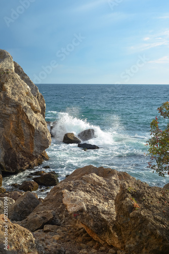 Waves of the Black Sea crash on a rocky shore on a sunny day in Crimea.