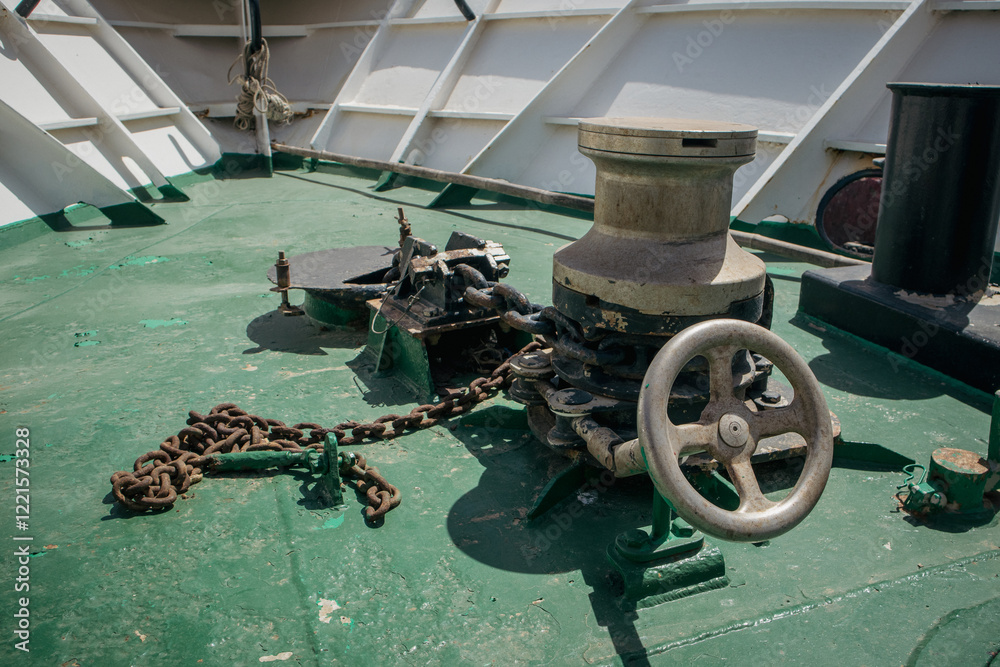 Wich with a chain for an achor on a steel ship. Visible command wheel and front part of the ship.