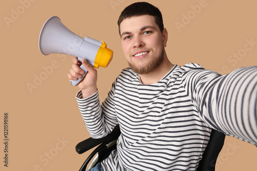 Young man in wheelchair with megaphone taking selfie on brown background, clo...