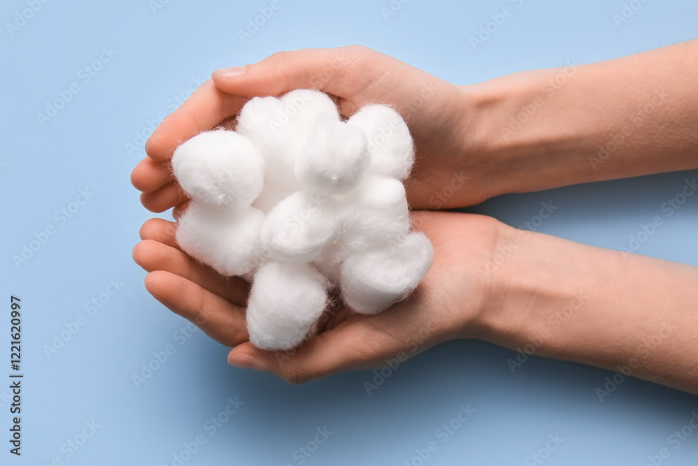 Female hands with cotton balls on blue background Female hands with cotton balls on blue background