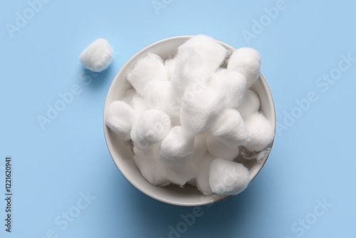 Bowl with cotton balls on blue background photo