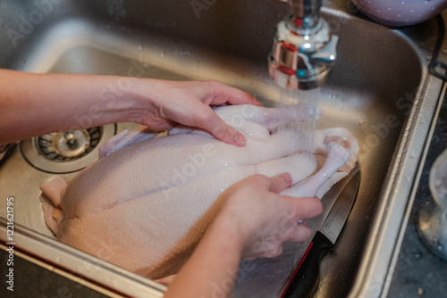 A woman washes chicken meat in a sink. General shot. photo