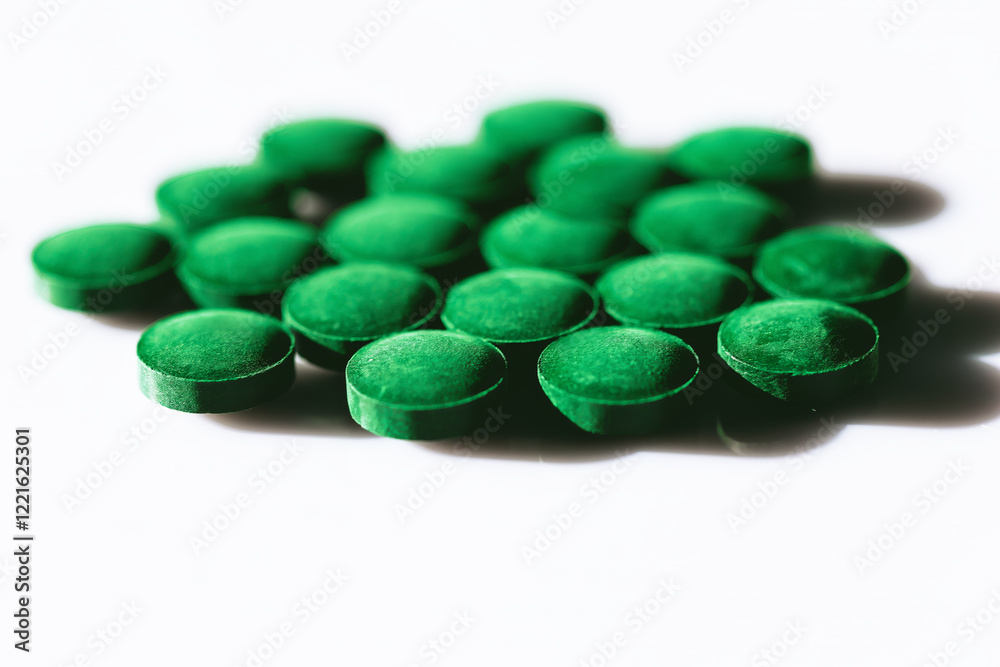 Green pills arranged on a white surface. Supplement tablets, showcasing a textured surface