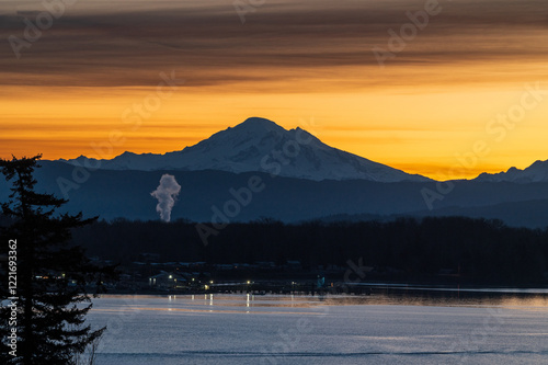 During a glorious sunrise Mt. Baker looms large over Hale Pass in the Salish Sea just before dawn. Gooseberry Point, on the mainland, hosts the ferry dock that services Lummi Island, Washington. photo