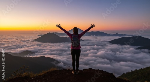 Wallpaper Mural A woman stands triumphantly on a mountain peak at sunrise, with clouds beneath.

 Torontodigital.ca
