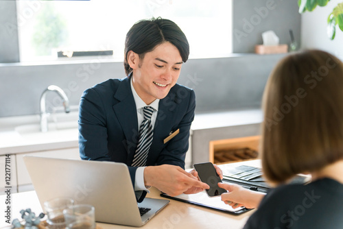 ハウスメーカーの展示場で打ち合わせ・プランニングをする男性ビジネスマンと女性客（リフォーム）
 photo