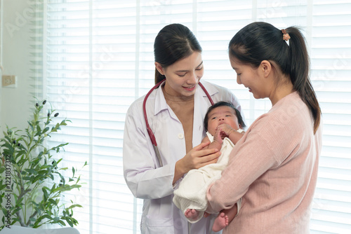 Fotografia Pediatric doctor interacting with mother holding newborn baby during health check in bright clinic
