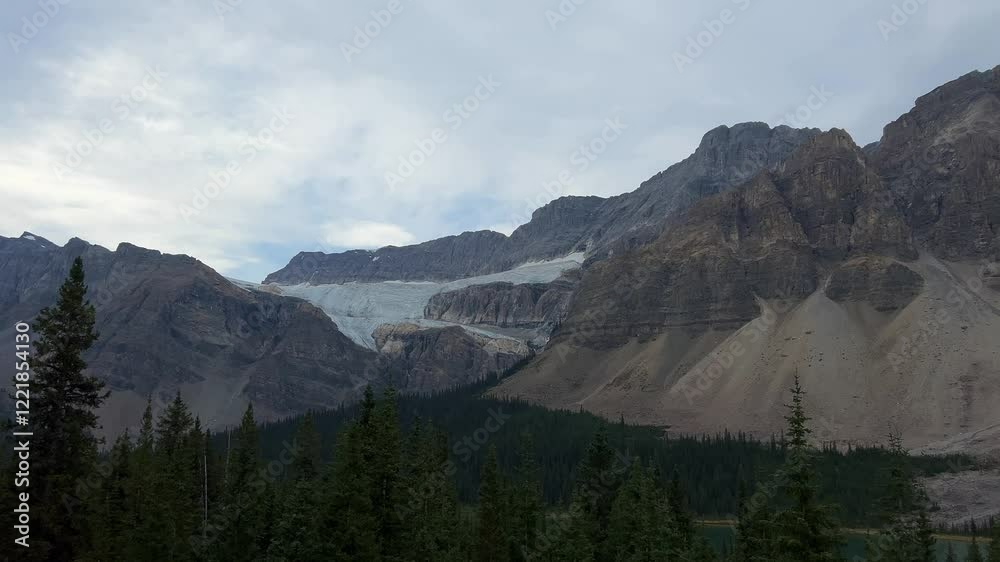 Sweeping view of tranquil lake framed by rugged mountains and a glacier under soft skies in Banff National Park, ideal for nature documentaries or travel promotions, Canada Sweeping view of tranquil lake framed by rugged mountains and a glacier under soft skies in Banff National Park, ideal for nature documentaries or travel promotions, Canada
