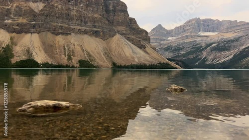 Scenic panning view of Bow Lake with surrounding mountains and clear blue water along Icefields Parkway, ideal for travel promotions and nature documentaries, Canada
