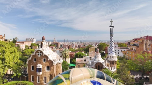 Iconic Park Güell architecture with vibrant ceramic mosaic tiles overlooking Barcelona on a sunny day. Pull Back Shot