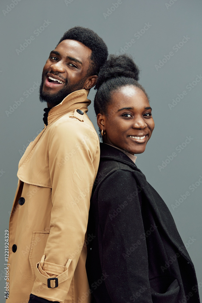 Obraz premium Happy young African couple smiling together, showcasing strong connection in modern fashion with neutral background