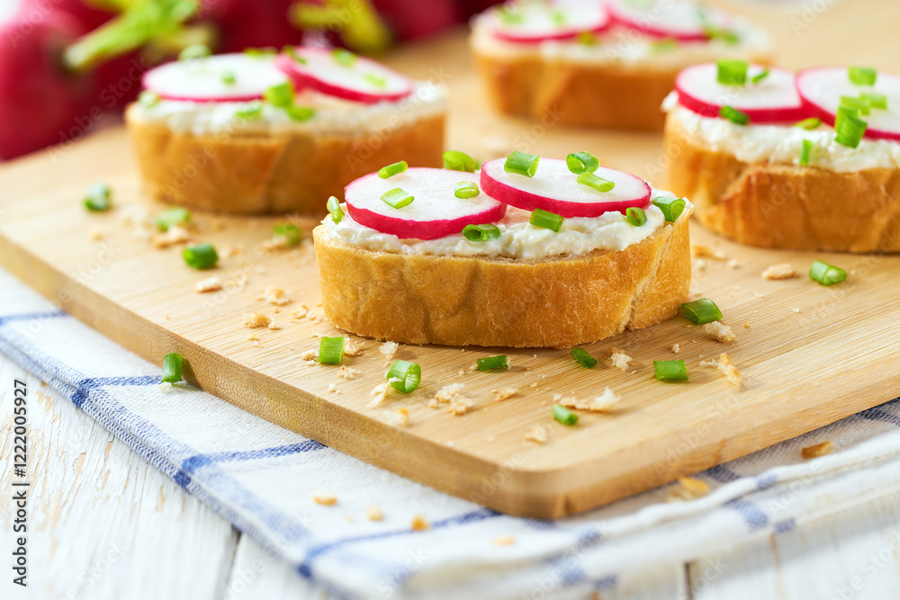 Cutting baguette with soft cream cheese and radish on a light kitchen table. Tasty summer snacks. Cutting baguette with soft cream cheese and radish on a light kitchen table. Tasty summer snacks.