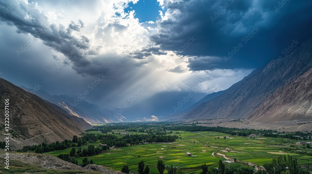 Naklejka premium Approaching storm clouds casting dramatic shadows over a green valley