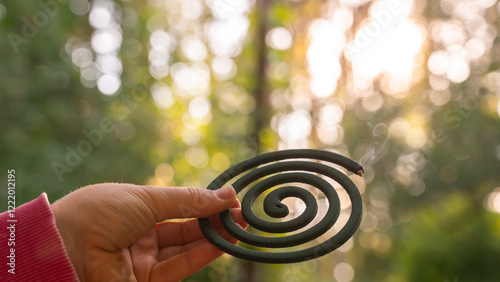 Green mosquito coil Insect repellent outdoors during summer. Trying to kill mosquitoes and flies. Prevention disinfection against mosquito bite during sunny day. 