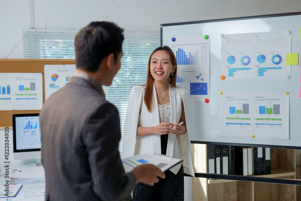 Asian businesspeople discussing company performance analyzing charts on whiteboard Asian businesspeople discussing company performance analyzing charts on whiteboard