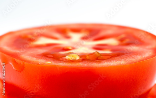 Sliced red tomato on white background. Round piece of fresh tomato. Macro background.