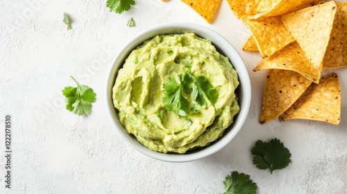 A bowl of fresh guacamole with a side of tortilla chips, guacamole centered in a simple white bowl, Overhead view with bright natural light