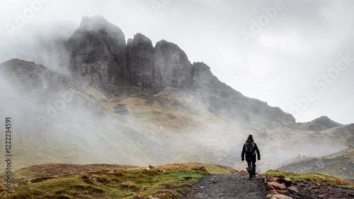 Woman with backpack hiking on a foggy path to the Old Man of Storr on the Isle of Skye, Scotland, UK