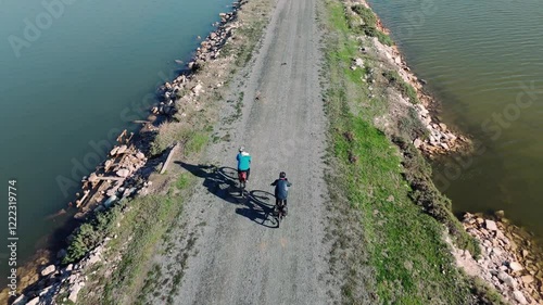Two cyclists enjoying a ride on a narrow path between water bodies. Bird Paradise, Izmir - Turkey