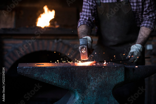 Close-up of blacksmith working with hammer at anvil in his workshop photo