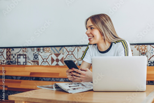 Young woman using the mobile phone and the laptop in cafe photo