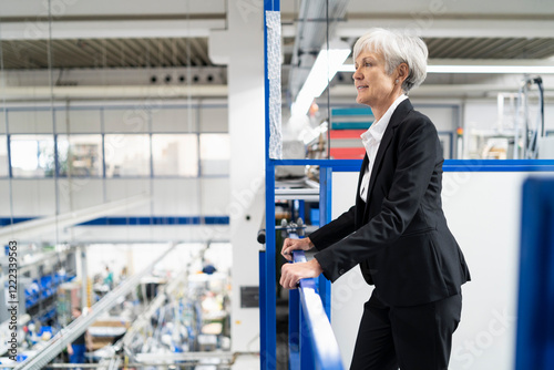 Senior businesswoman on upper floor in factory overlooking shop floor photo