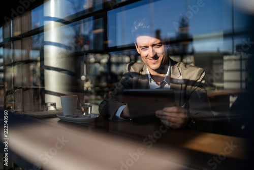 Businessman using tablet behind the window in a cafe