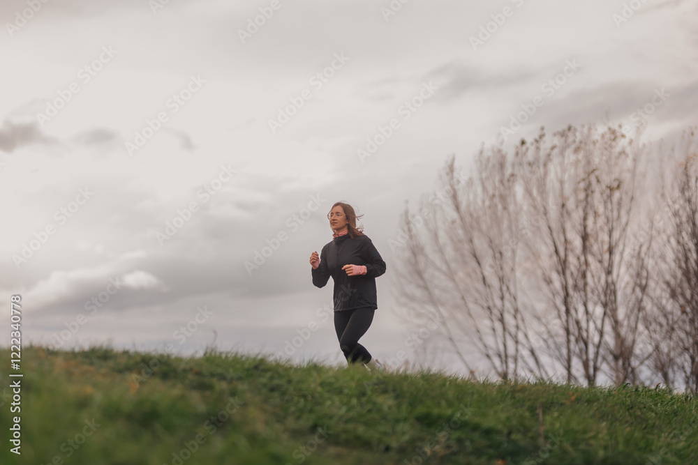 Woman jogging in a park during a cloudy day Woman jogging in a park during a cloudy day