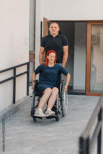 Nurse assisting patient in wheelchair up ramp at hospital entrance photo