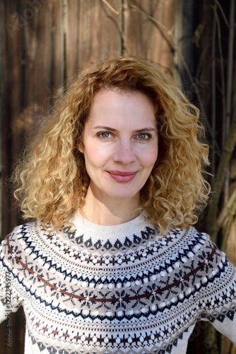 Blonde woman with curly hair smiling, norwegian sweater photo