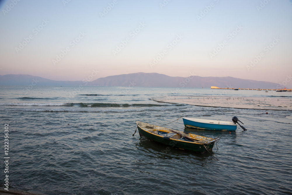 Boats anchored peacefully in the tranquil waters of Albania's coastline during sunset in the early evening Boats anchored peacefully in the tranquil waters of Albania's coastline during sunset in the early evening
