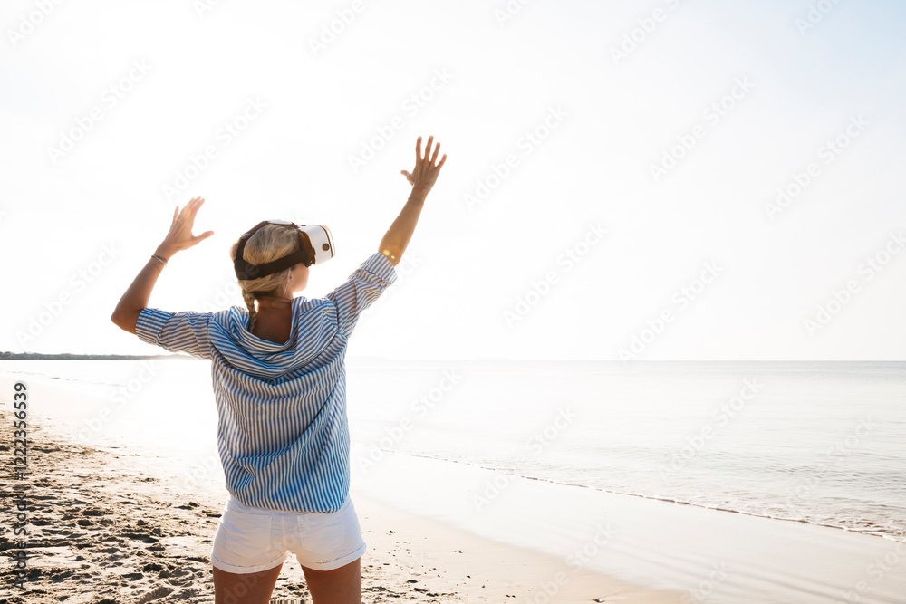 Thailand, woman using virtual reality glasses on the beach in the morning light Thailand, woman using virtual reality glasses on the beach in the morning light