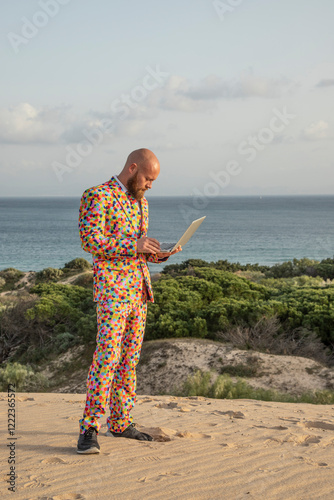 Man wearing suit with colourful polka-dots using laptop outdoors photo