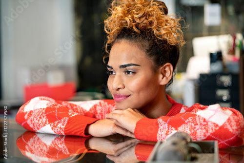 Young woman working in fashion store, leaning on counter
