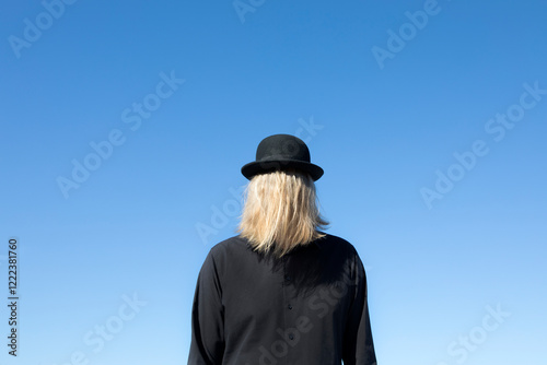 Blond hair covering man's face wearing bowler hat photo