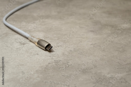 Micro USB charging cable on gray background. Charging cord for household electrical appliances